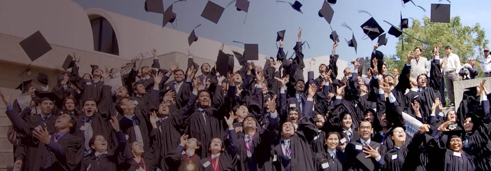 IBMR graduates throwing their caps into the air